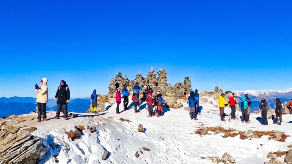 Trekkers climbing the snowy Kedarkantha summit in Uttarakhand